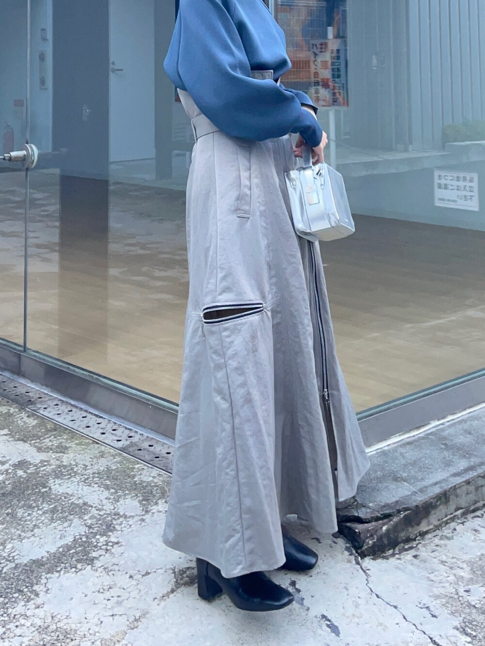 グレー系のニット/セーター、グレー系のスカート、シルバー系のショルダーバッグを着用したレディースの秋コーディネートの4枚目の写真