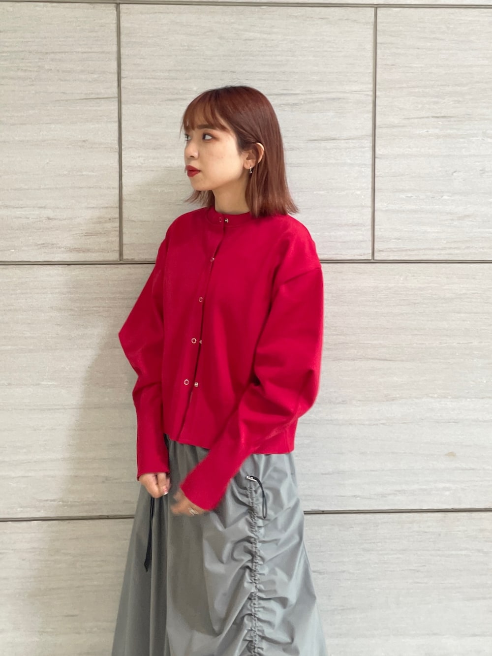 グレー系のスカート、レッド系のカーディガン/ボレロ、ブラウン系のブーツを着用したレディースの秋コーディネートの3枚目の写真