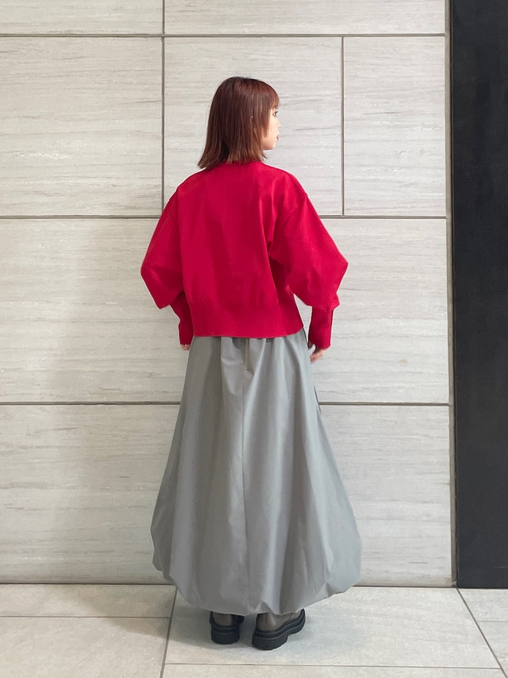 グレー系のスカート、レッド系のカーディガン/ボレロ、ブラウン系のブーツを着用したレディースの秋コーディネートの2枚目の写真