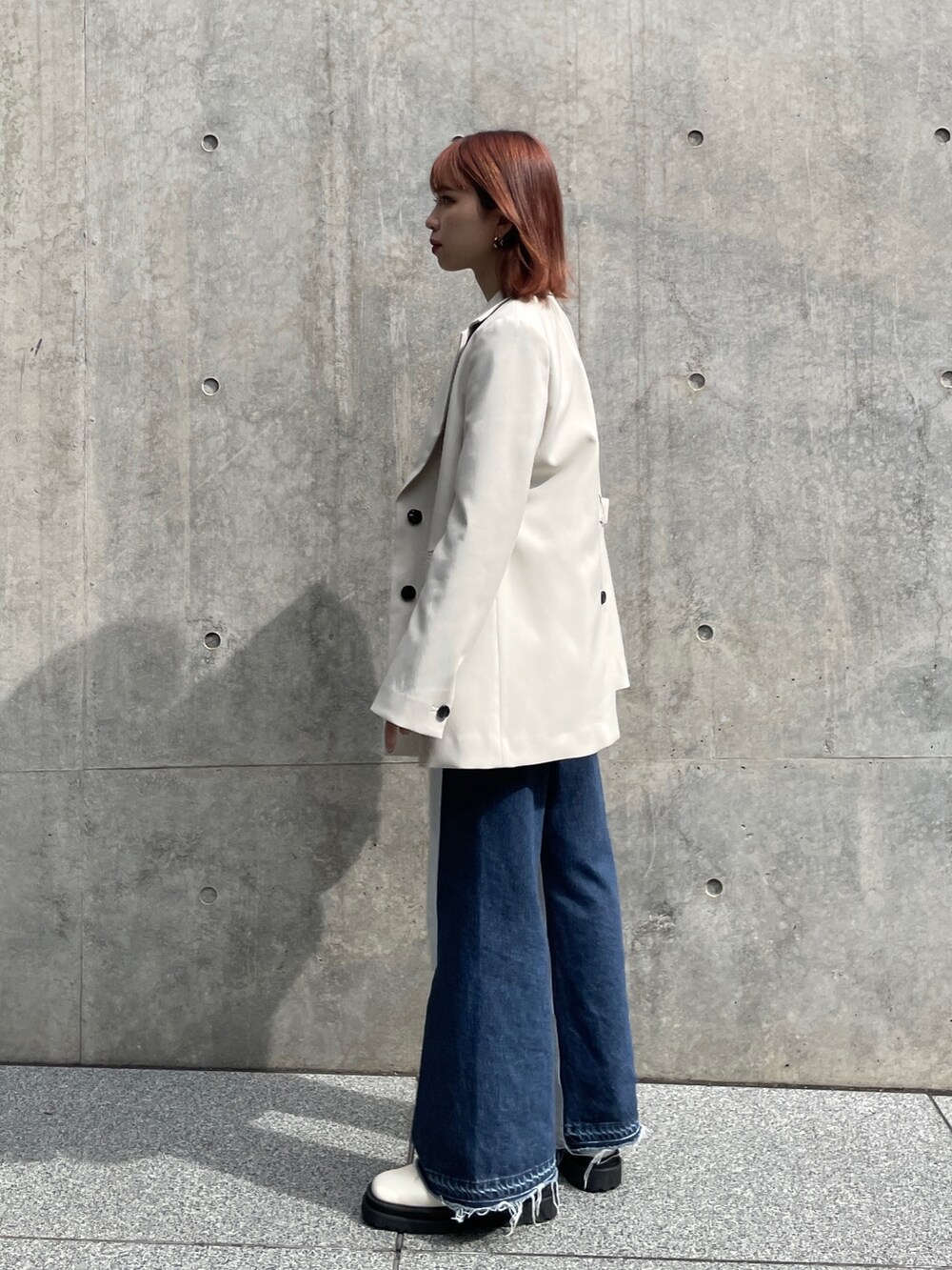 ベージュ系のテーラードジャケット、グレー系のニット/セーター、ブルー系のデニムパンツを着用したレディースの秋コーディネートの5枚目の写真