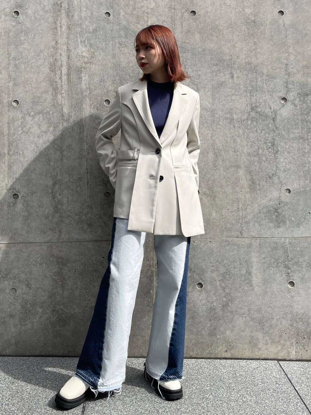 ベージュ系のテーラードジャケット、グレー系のニット/セーター、ブルー系のデニムパンツを着用したレディースの秋コーディネートの2枚目の写真