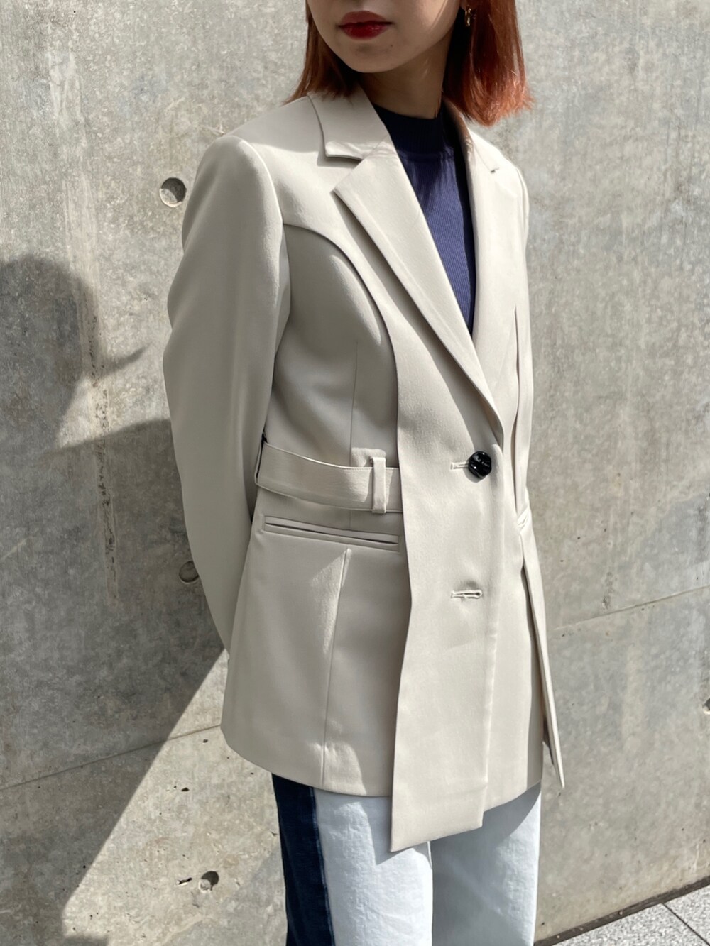 ベージュ系のテーラードジャケット、グレー系のニット/セーター、ブルー系のデニムパンツを着用したレディースの秋コーディネートの4枚目の写真