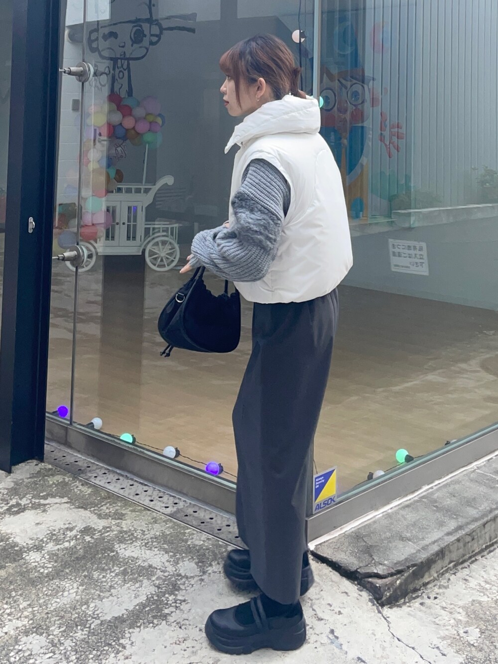 グレー系のスカート、ホワイト系のダウンジャケット/コート、ブラック系のショルダーバッグを着用したレディースの冬コーディネートの2枚目の写真