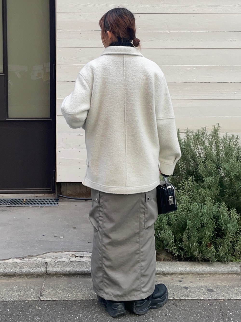 ホワイト系のブルゾン、ブラック系のショルダーバッグ、グレー系のスカートを着用したレディースの冬コーディネートの2枚目の写真