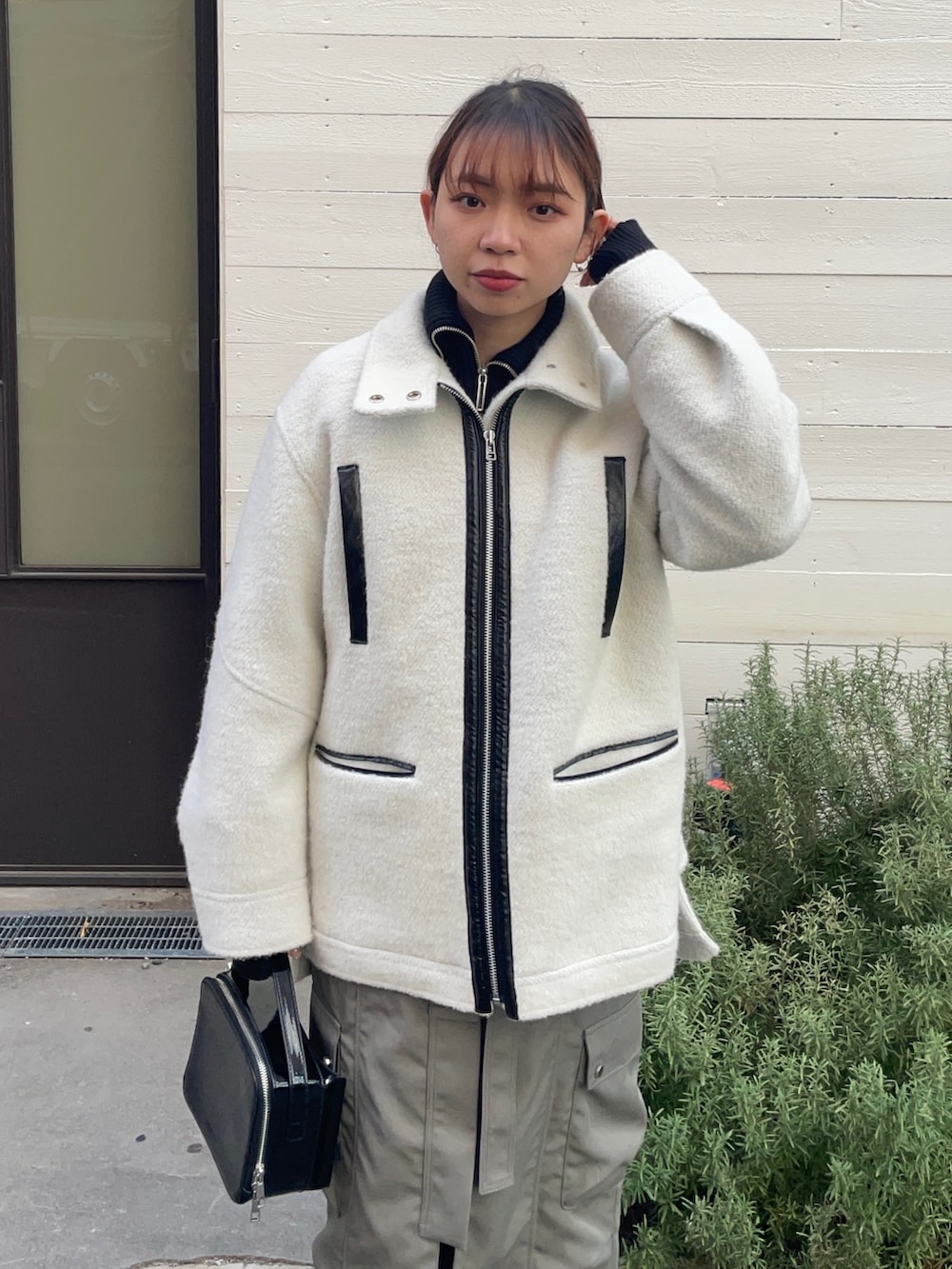 ホワイト系のブルゾン、ブラック系のショルダーバッグ、グレー系のスカートを着用したレディースの冬コーディネートの3枚目の写真