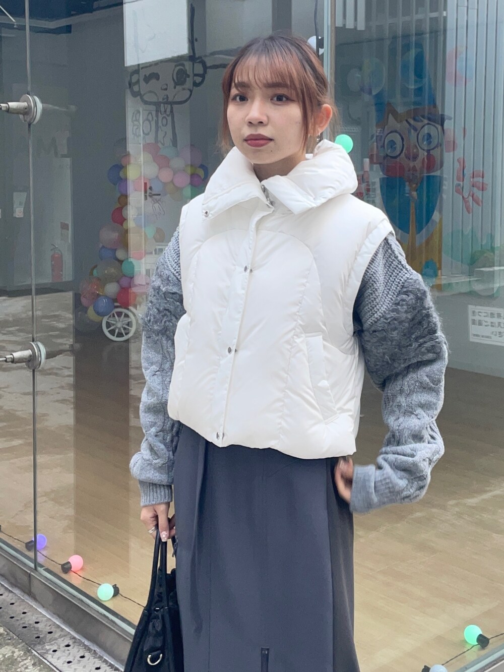 グレー系のスカート、ホワイト系のダウンジャケット/コート、ブラック系のショルダーバッグを着用したレディースの冬コーディネートの4枚目の写真
