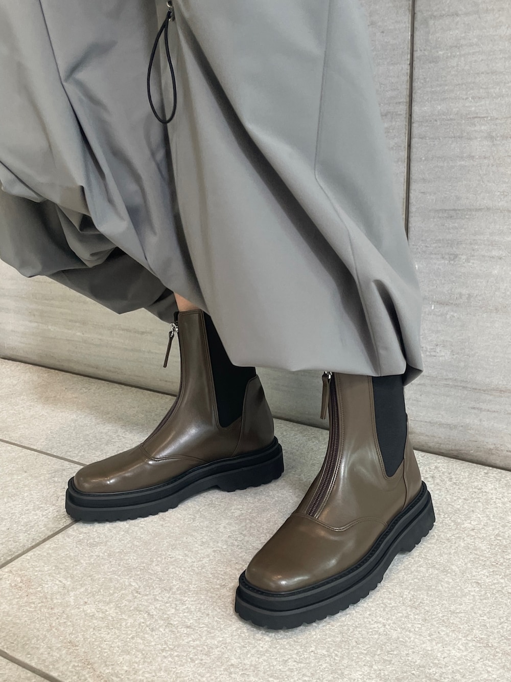 グレー系のスカート、レッド系のカーディガン/ボレロ、ブラウン系のブーツを着用したレディースの秋コーディネートの5枚目の写真