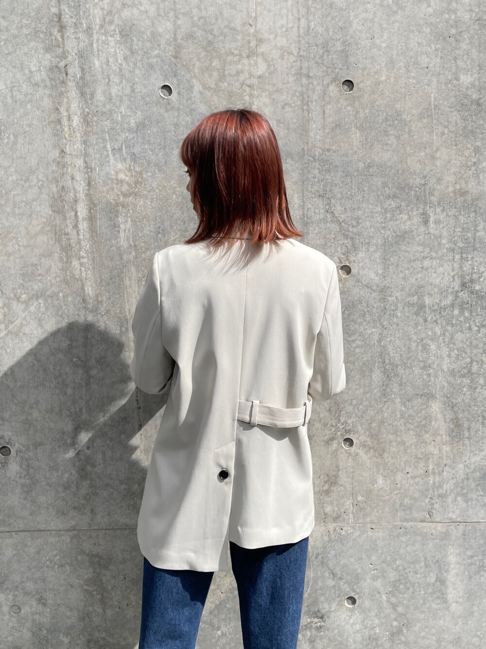 ベージュ系のテーラードジャケット、グレー系のニット/セーター、ブルー系のデニムパンツを着用したレディースの秋コーディネートの3枚目の写真