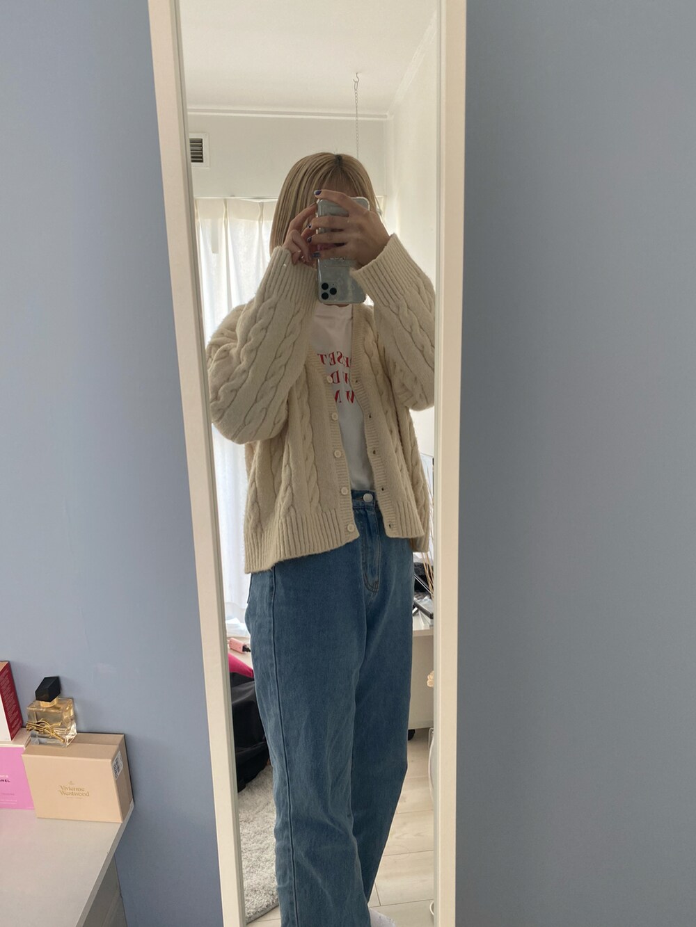 ホワイト系のニット/セーター、ブルー系のデニムパンツ、ホワイト系のTシャツ/カットソーを着用したレディースの冬コーディネートの2枚目の写真