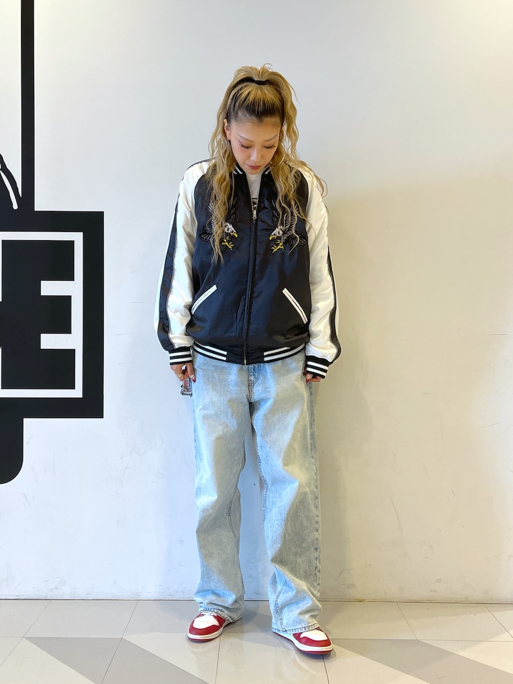 ブラック系のスカジャン、ブルー系のデニムパンツを着用したレディースの秋コーディネートの2枚目の写真