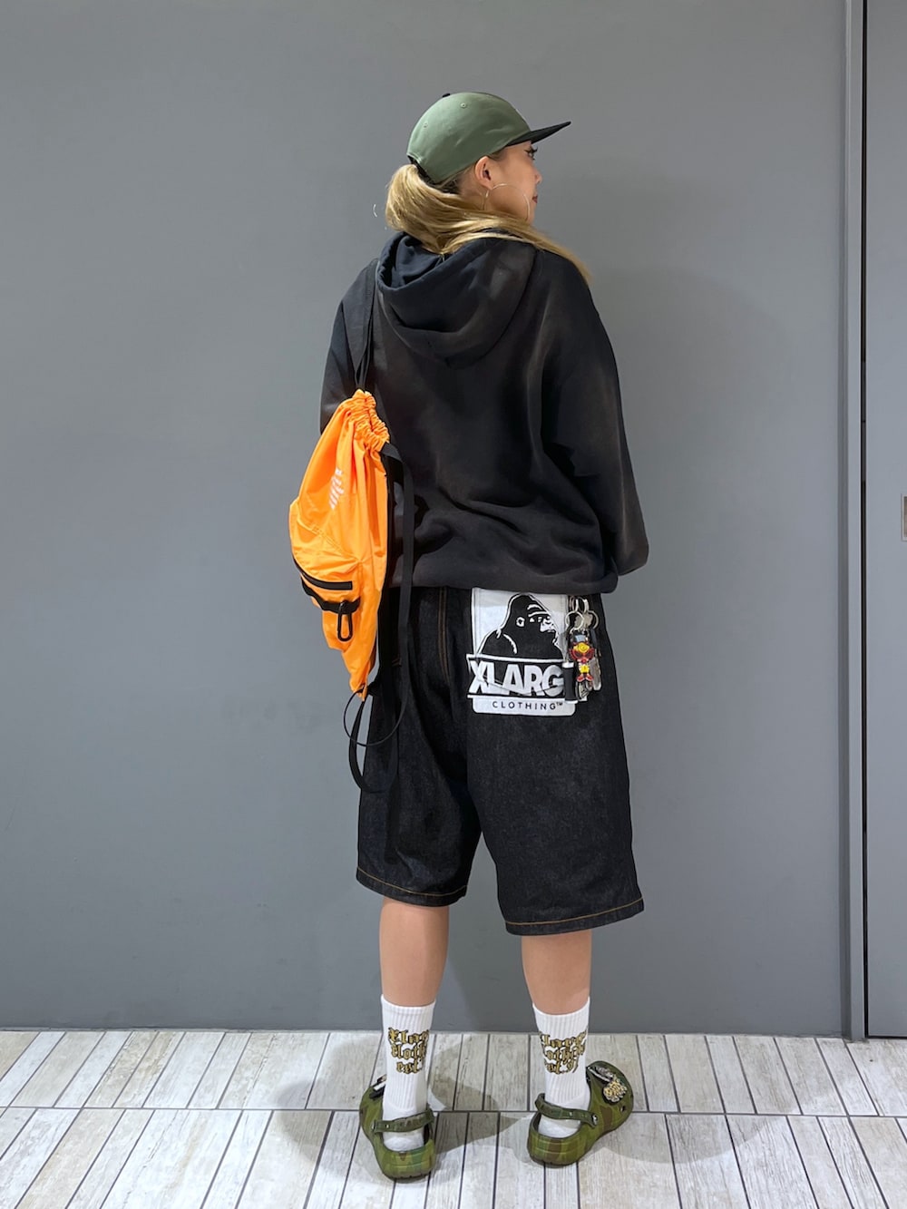 ブラック系のパーカー、ブラック系のデニムパンツ、グリーン系のキャップを着用したレディースの夏コーディネートの2枚目の写真