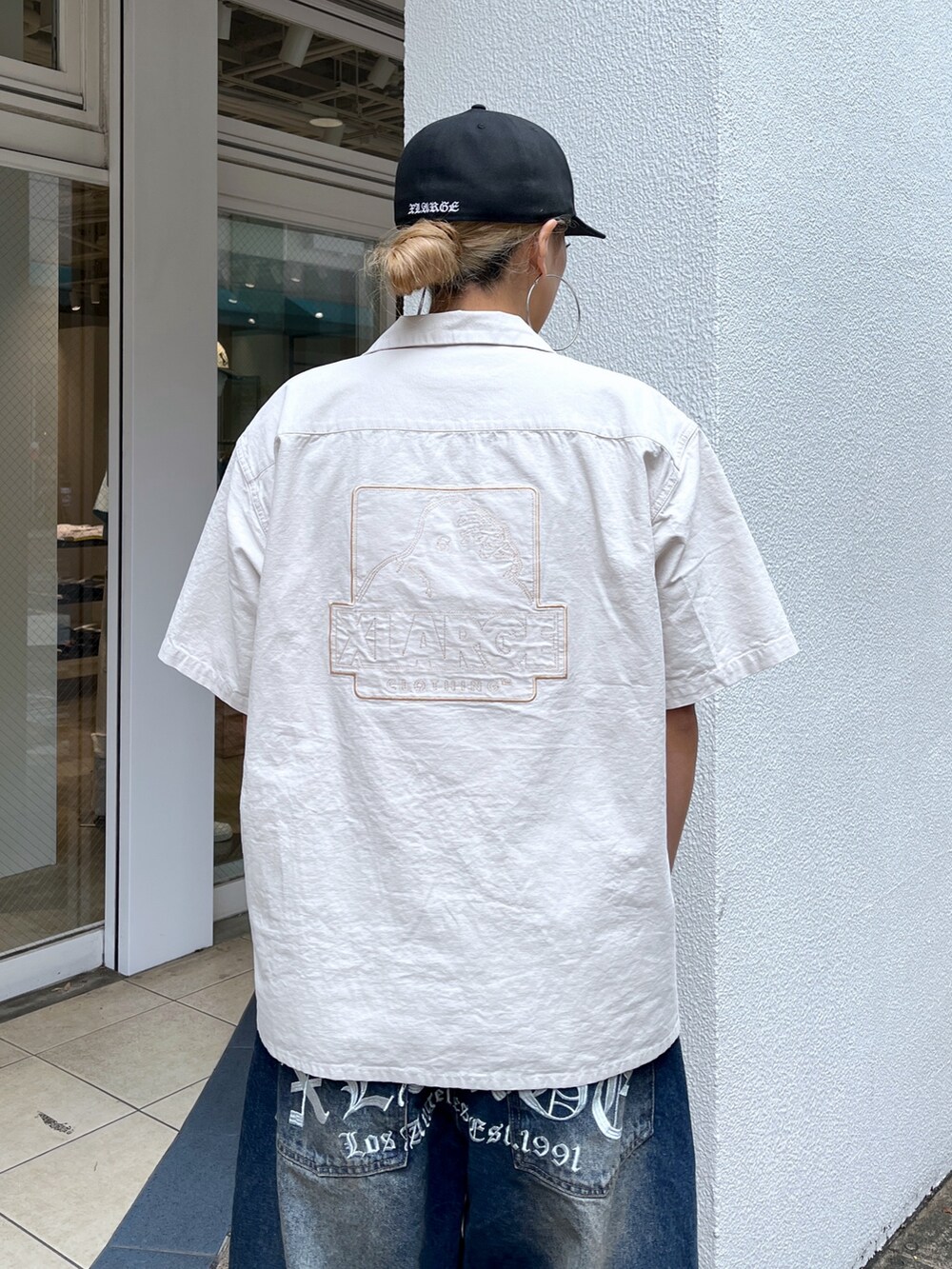 ベージュ系のシャツ/ブラウス、ブルー系のデニムパンツ、ブラック系のスニーカーを着用したレディースの春コーディネートの5枚目の写真