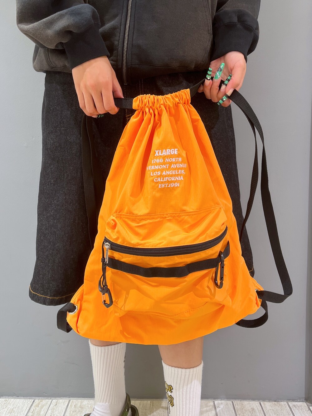 ブラック系のパーカー、ブラック系のデニムパンツ、グリーン系のキャップを着用したレディースの夏コーディネートの3枚目の写真