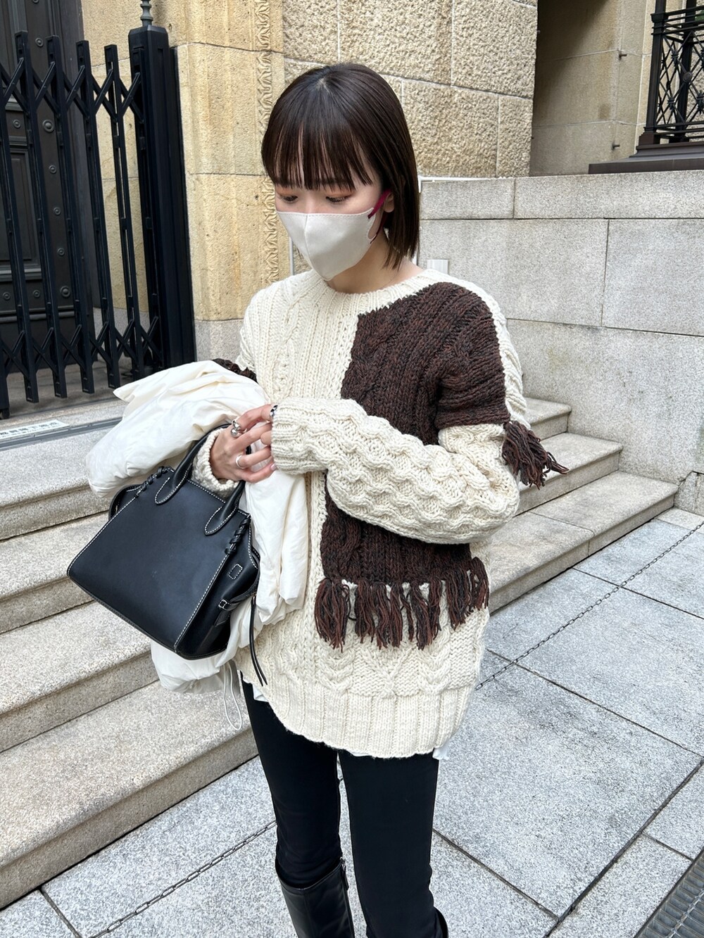 ホワイト系のニット/セーター、ホワイト系のダウンジャケット/コート、ブラック系のハンドバッグを着用したレディースの冬コーディネートの2枚目の写真