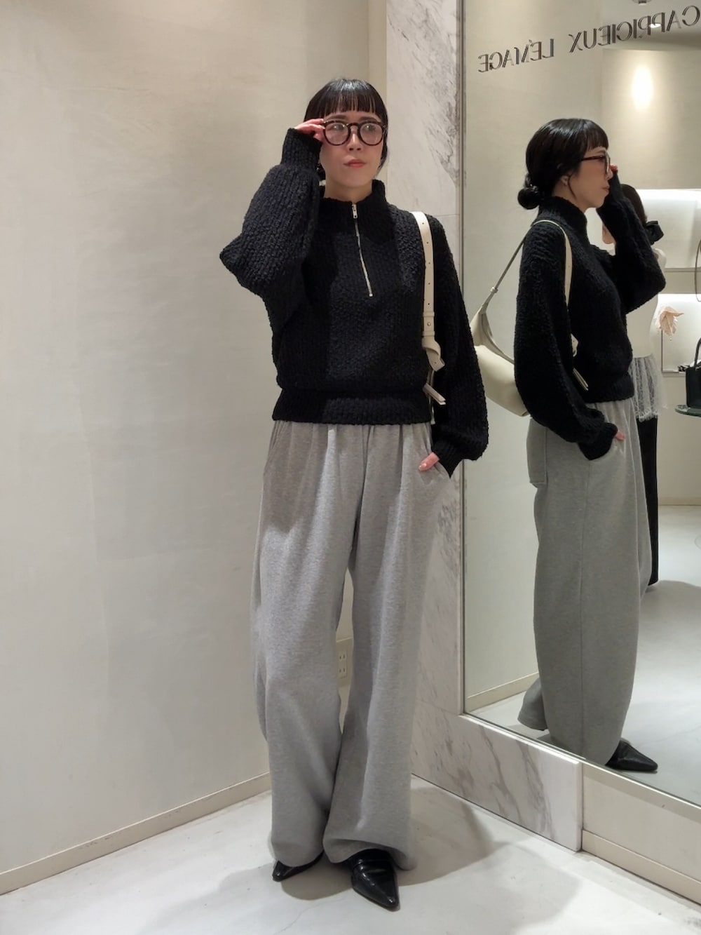 ブラック系のニット/セーター、ホワイト系のショルダーバッグ、グレー系のスウェットパンツを着用したレディースの冬コーディネートの2枚目の写真