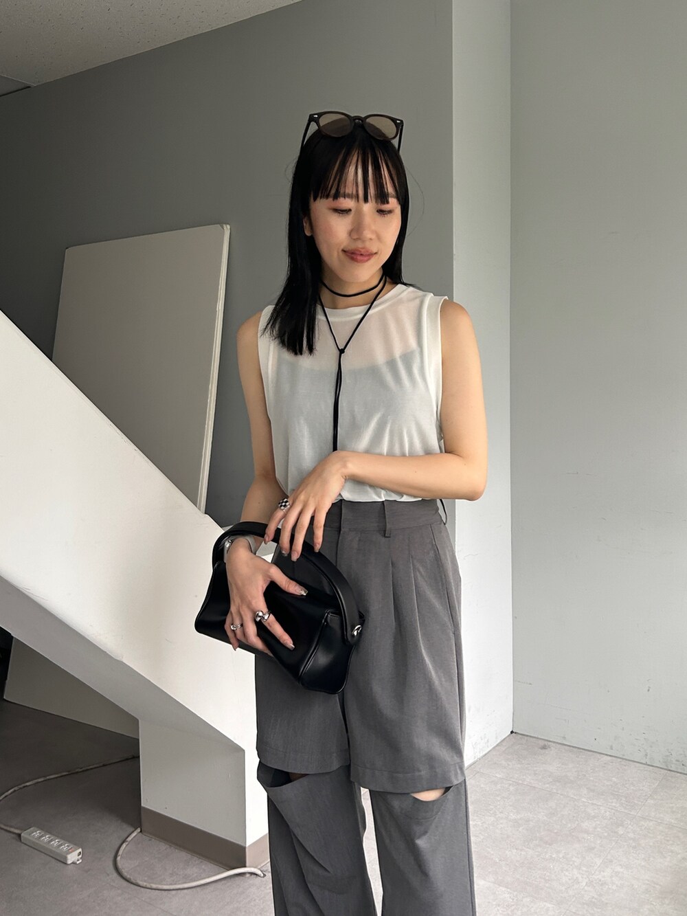 グレー系のパンツ、ホワイト系のTシャツ/カットソー、ブラック系のショルダーバッグを着用したレディースの夏コーディネートの2枚目の写真