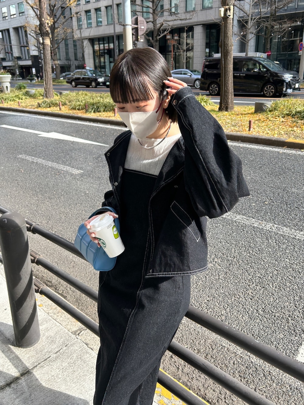 ブルー系のハンドバッグ、ブラック系のデニムジャケット、ホワイト系のスニーカーを着用したレディースの冬コーディネートの2枚目の写真