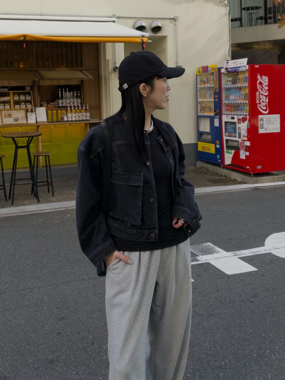 グレー系のスウェットパンツ、ブラック系のデニムジャケット、ブラック系のキャップを着用したレディースの冬コーディネートの2枚目の写真