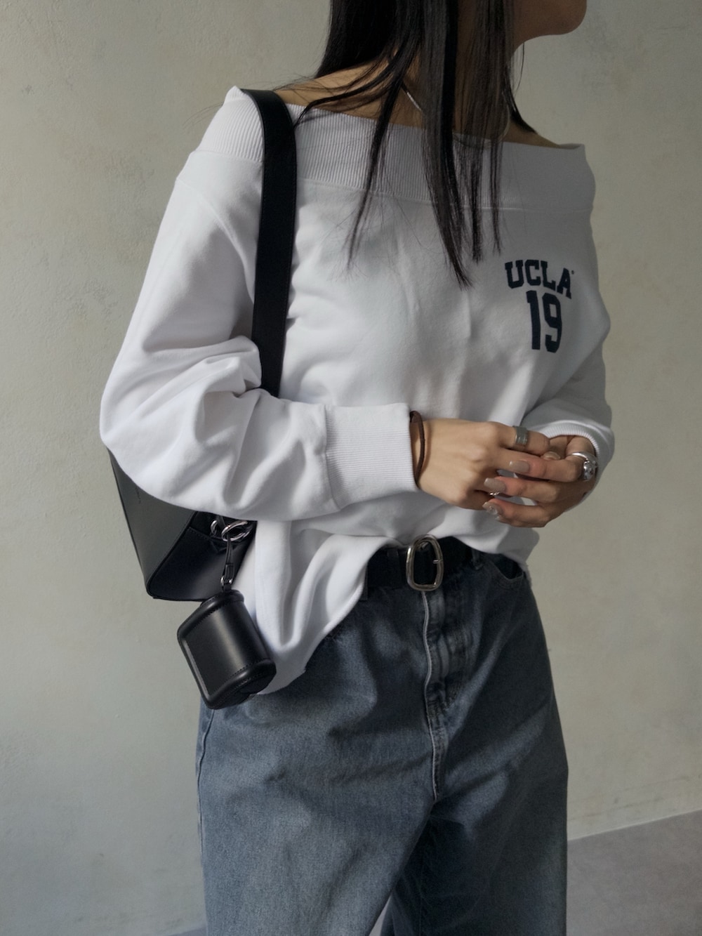 ブラック系のショルダーバッグ、ホワイト系のTシャツ/カットソー、ブルー系のデニムパンツを着用したレディースの冬コーディネートの2枚目の写真