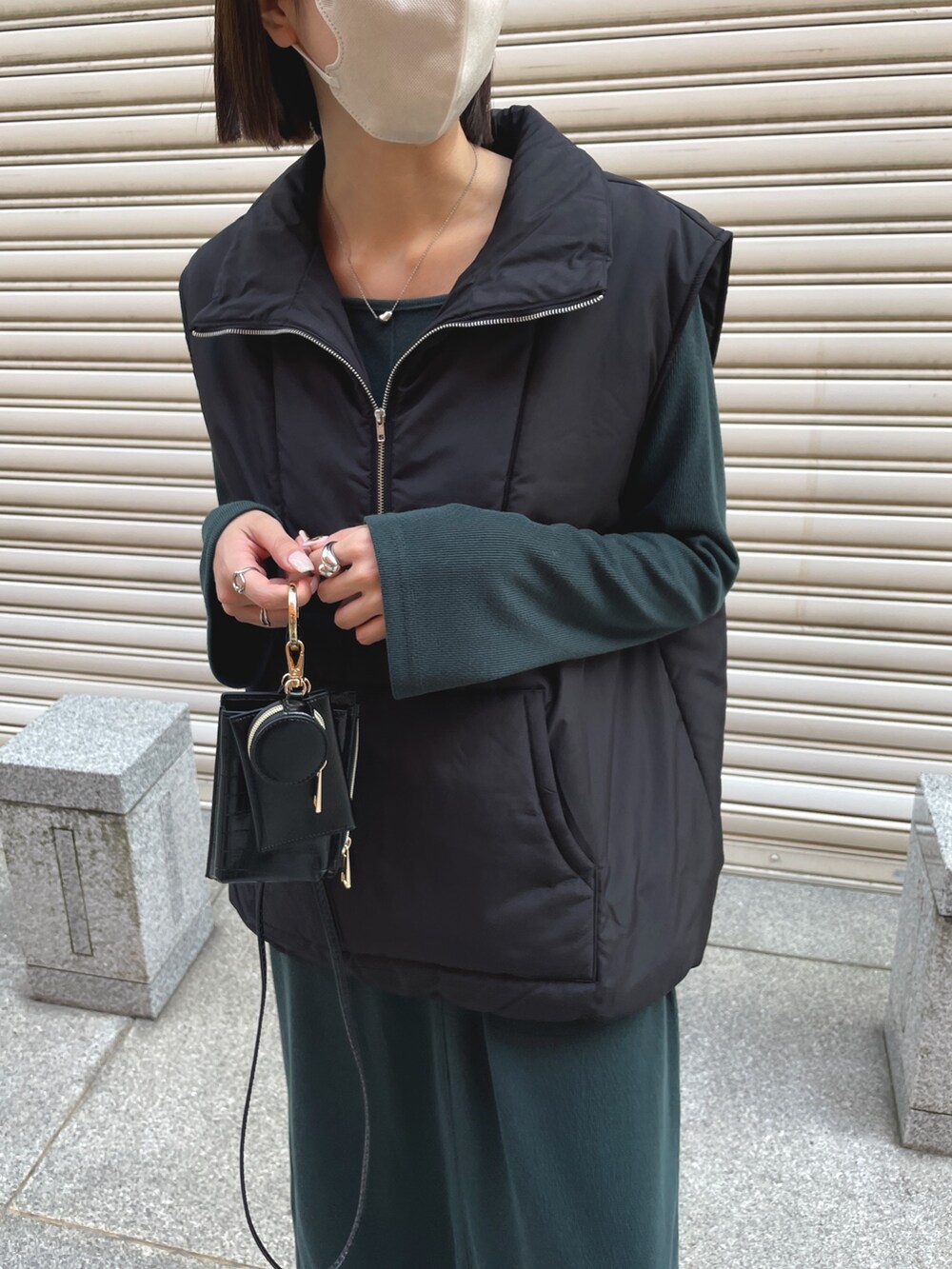 ブラック系のダウンベスト、ブラック系のブーツ、グリーン系のワンピースを着用したレディースの秋コーディネートの2枚目の写真