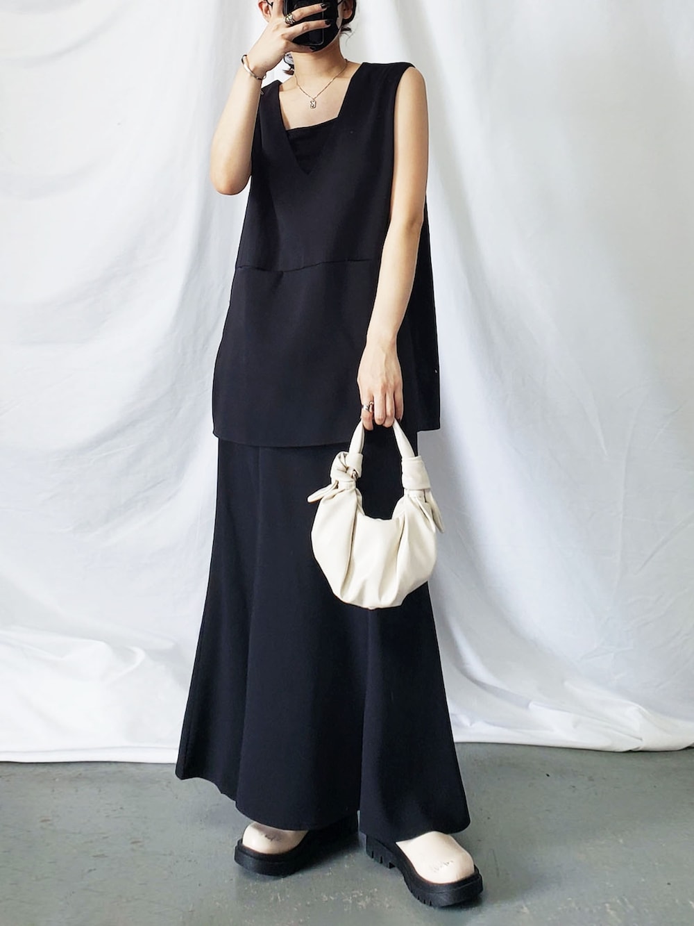 ホワイト系のベスト、ブラック系のスラックスを着用したレディースの夏コーディネートの2枚目の写真