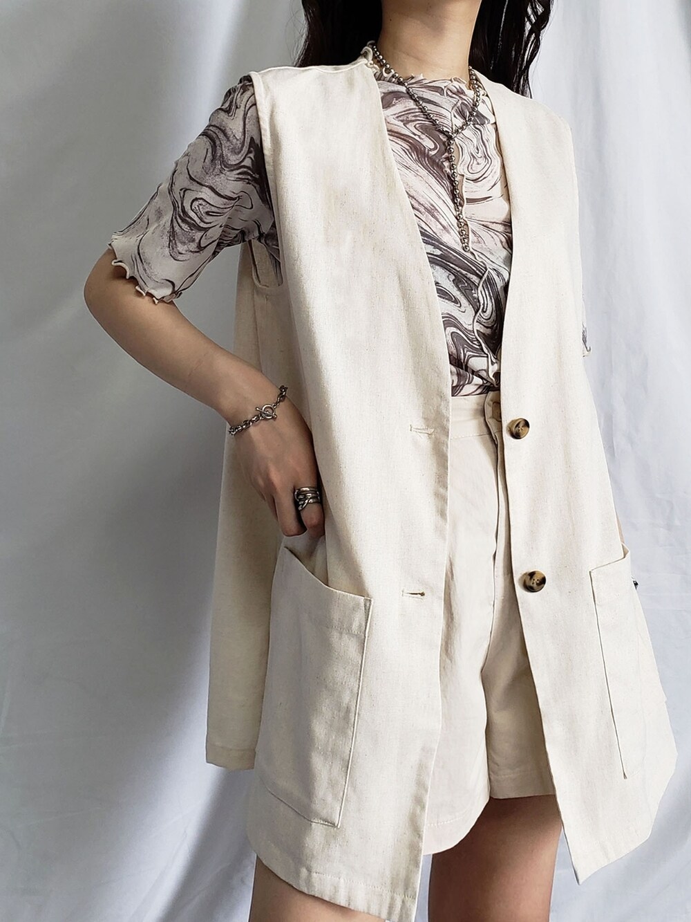 グリーン系のスカート、ブラック系のベストを着用したレディースの夏コーディネートの4枚目の写真