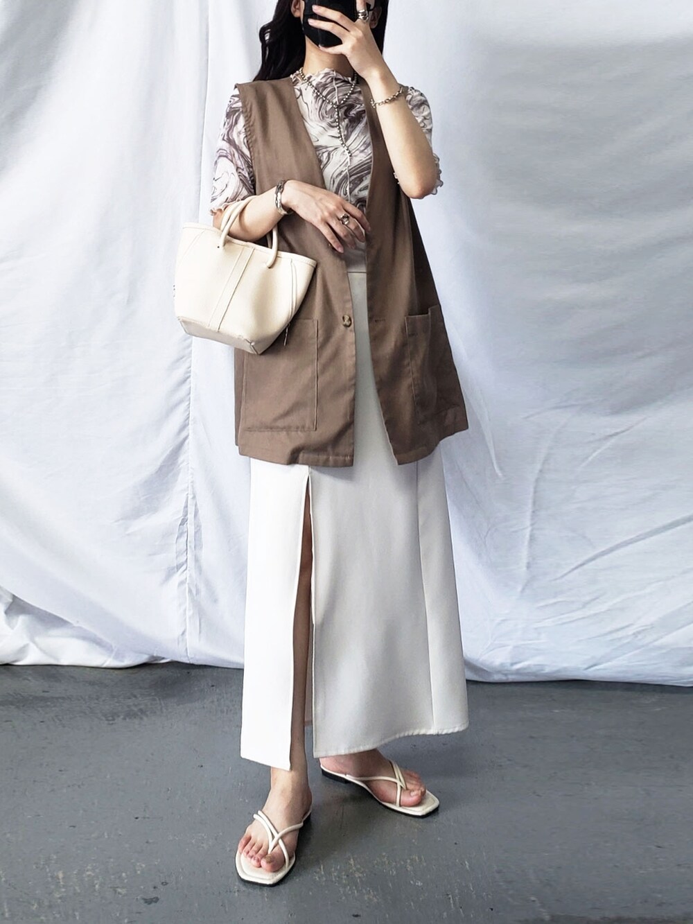 グリーン系のスカート、ブラック系のベストを着用したレディースの夏コーディネートの2枚目の写真