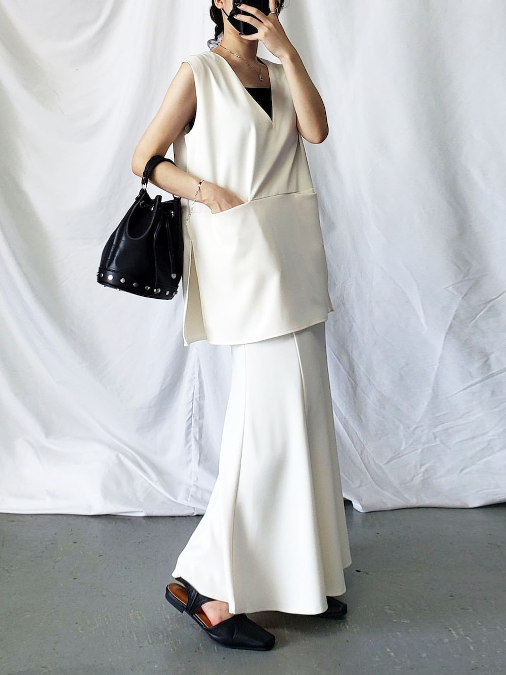 ホワイト系のベスト、ブラック系のスラックスを着用したレディースの夏コーディネートの3枚目の写真