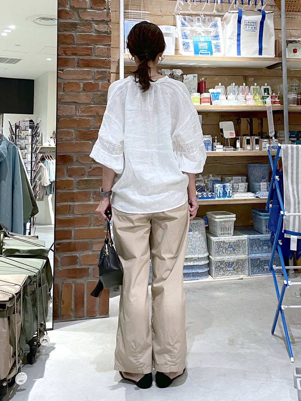 ブラック系のサンダル、ブラック系のショルダーバッグ、ベージュ系のキャミソールを着用したレディースの夏コーディネートの3枚目の写真