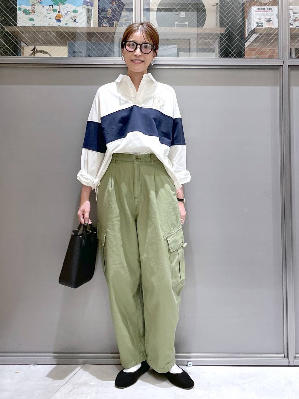 ブラック系のトートバッグ、ブラック系のパンプス、グリーン系のカーゴパンツを着用したレディースの春コーディネートの6枚目の写真