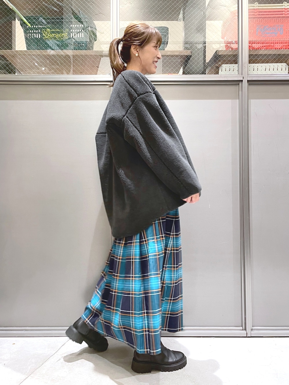 ベージュ系のニット/セーター、グレー系のブルゾン、ブルー系のスカートを着用したレディースの秋コーディネートの2枚目の写真