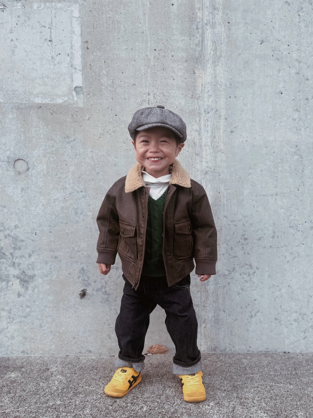 ブラウン系のジャケット/アウター、ブルー系のデニムパンツ、イエロー系のスニーカーを着用したキッズの冬コーディネートの2枚目の写真