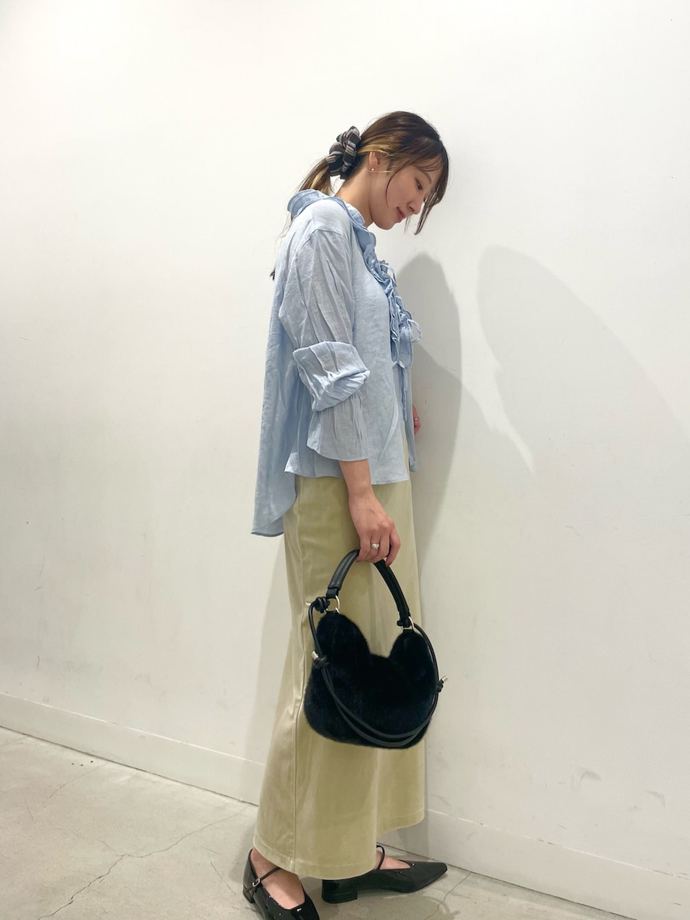 ブラック系のパンプス、ブラック系のショルダーバッグ、ベージュ系のスカートを着用したレディースの秋コーディネートの2枚目の写真