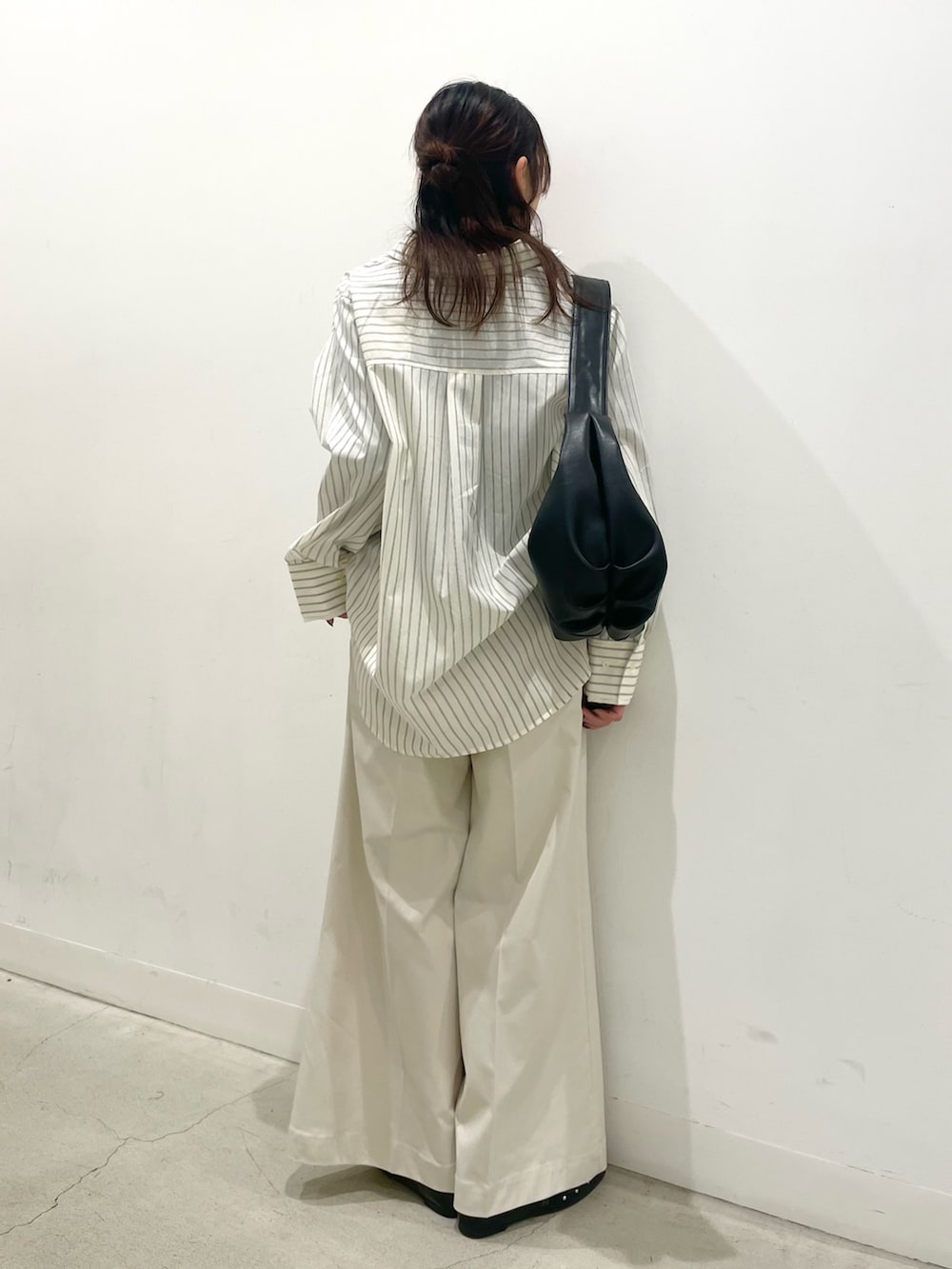 ブラック系のパンプス、ブラック系のショルダーバッグ、ホワイト系のチノパンツを着用したレディースの冬コーディネートの3枚目の写真