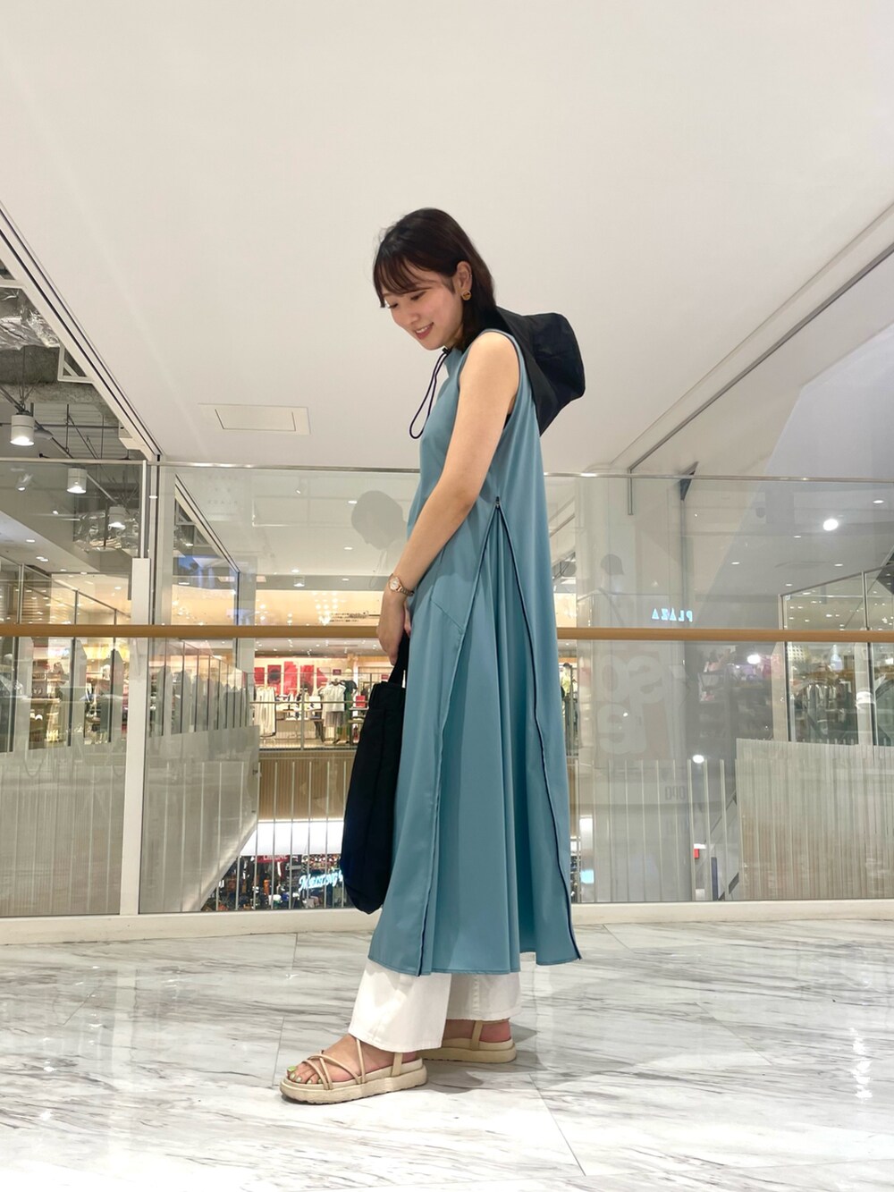 ブルー系のワンピース、ブラック系のショルダーバッグ、ホワイト系のデニムパンツを着用したレディースの夏コーディネートの2枚目の写真