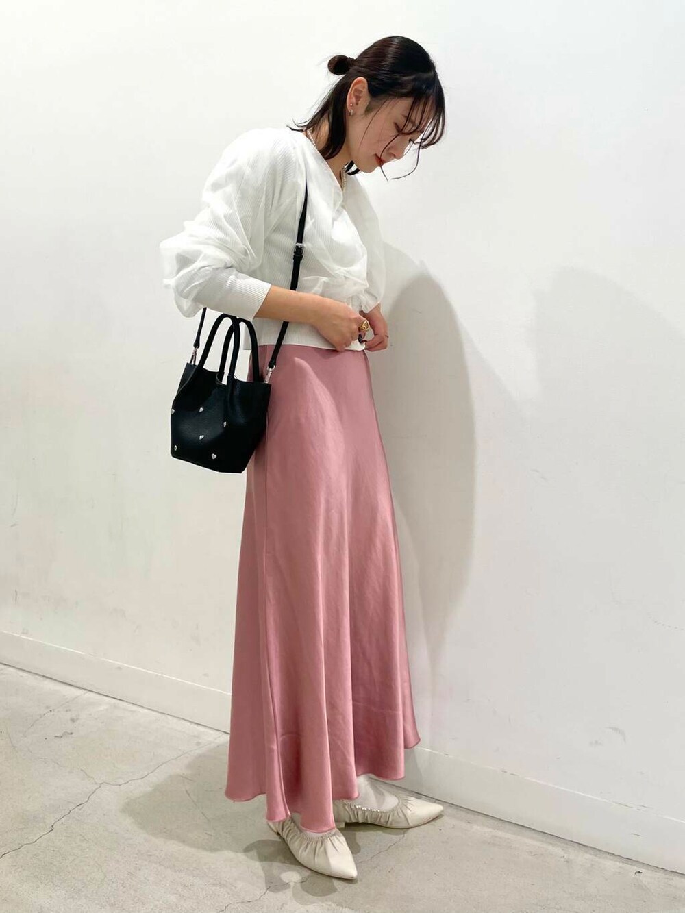 ピンク系のスカート、ブラック系のショルダーバッグ、ホワイト系のバレエシューズを着用したレディースの冬コーディネートの2枚目の写真