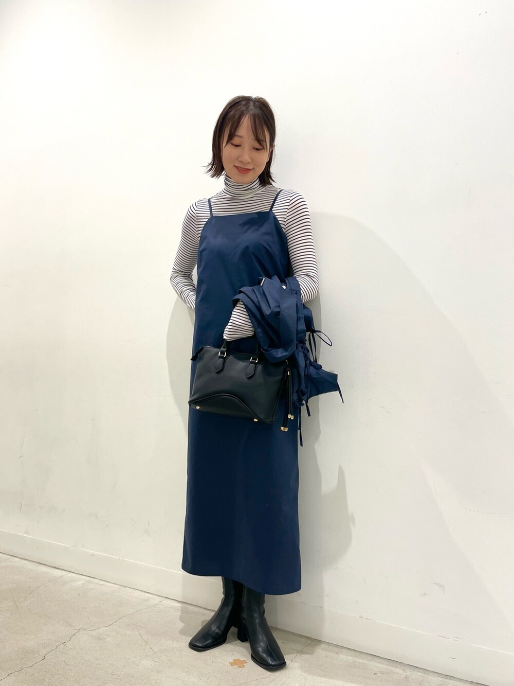 ホワイト系のTシャツ/カットソー、ブルー系のワンピース、ブラック系のブーツを着用したレディースの秋コーディネートの2枚目の写真