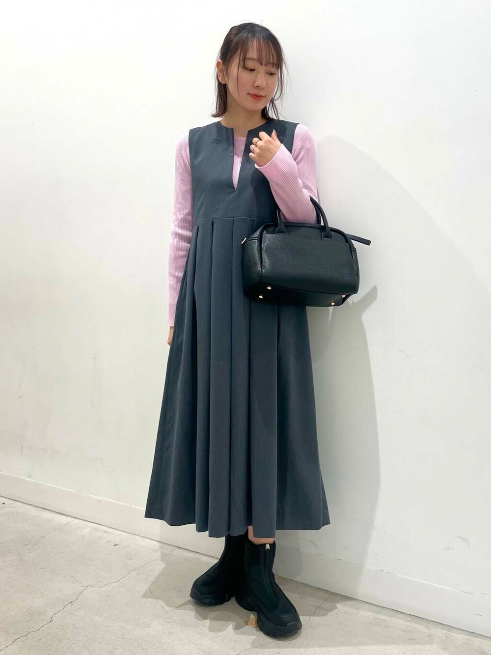 ブラック系のボストンバッグ、グレー系のワンピース、ブラック系のブーツを着用したレディースの冬コーディネートの2枚目の写真