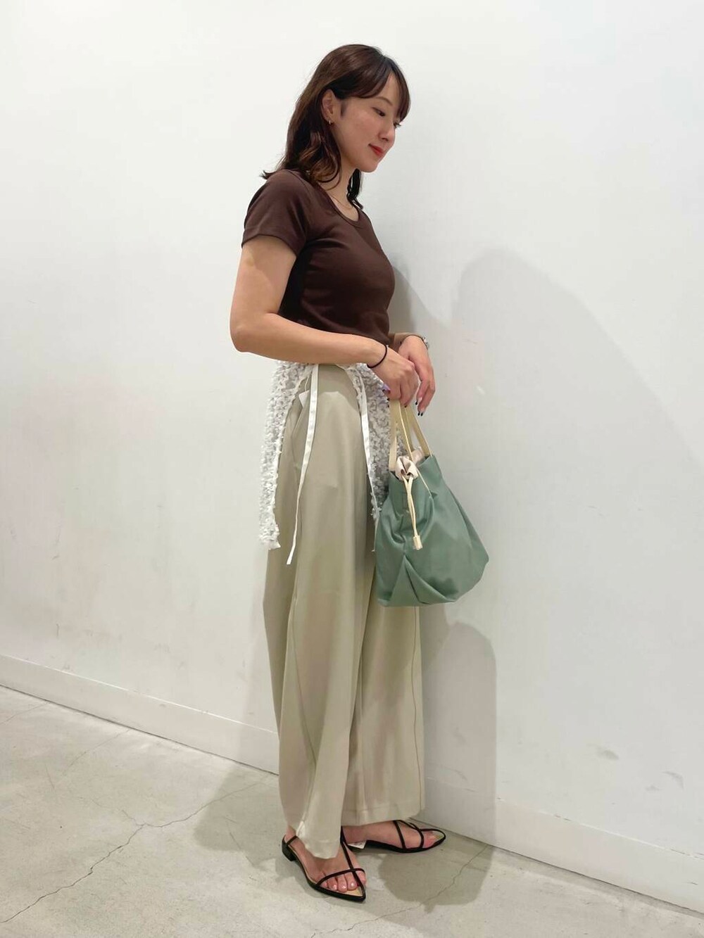 ブラック系のサンダル、ホワイト系のスカート、ベージュ系のその他パンツを着用したレディースの夏コーディネートの2枚目の写真