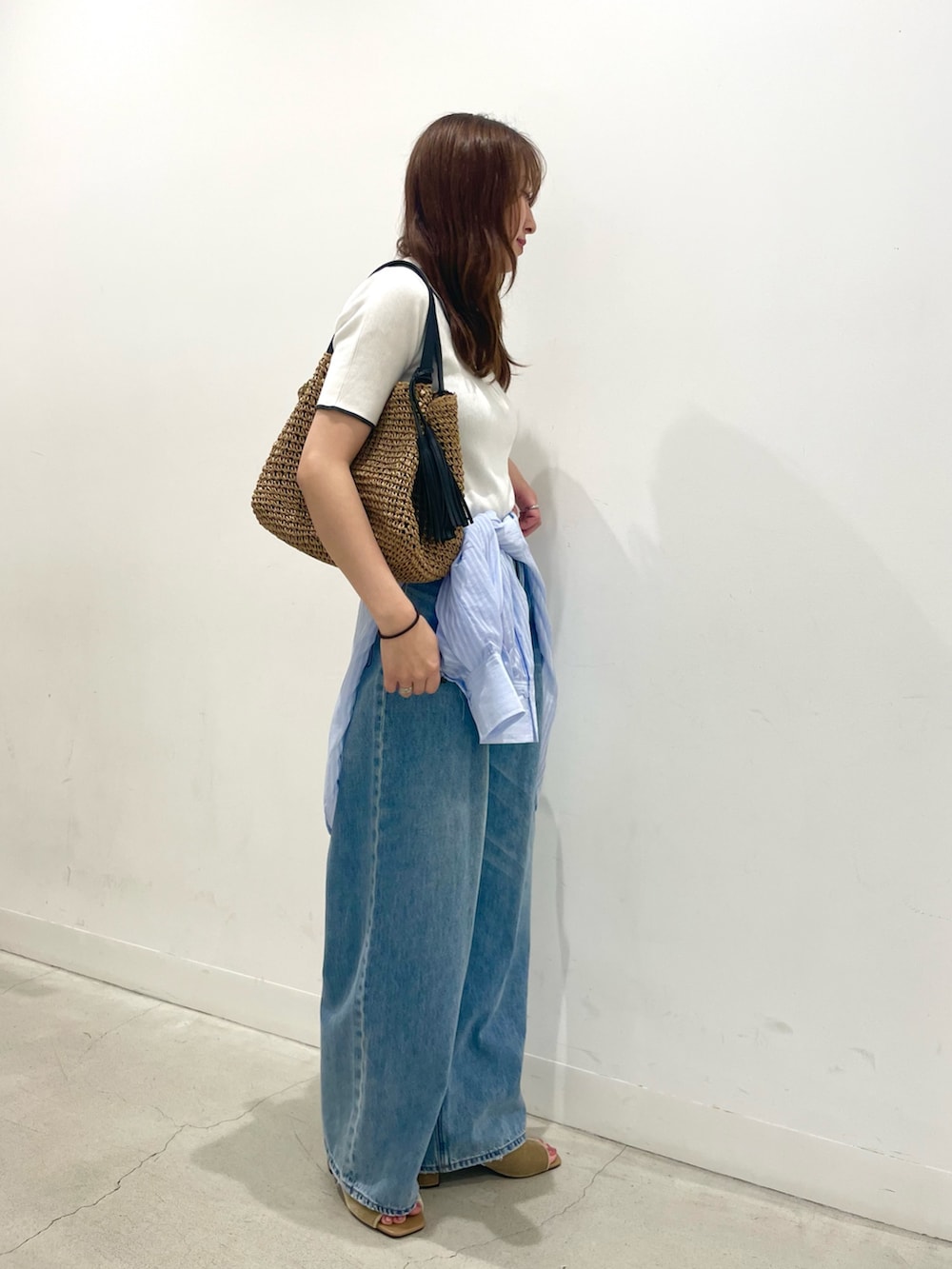 ベージュ系のサンダル、イエロー系のかごバッグ、ブルー系のデニムパンツを着用したレディースの夏コーディネートの2枚目の写真