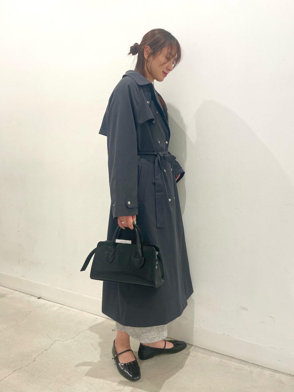 ブラック系のパンプス、ブラック系のボストンバッグ、グレー系のワンピースを着用したレディースの春コーディネートの2枚目の写真