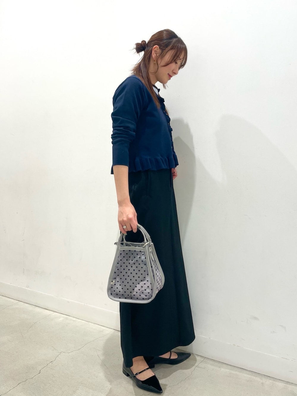 ブラック系のパンプス、グレー系のハンドバッグ、ブラック系のスカートを着用したレディースの春コーディネートの2枚目の写真