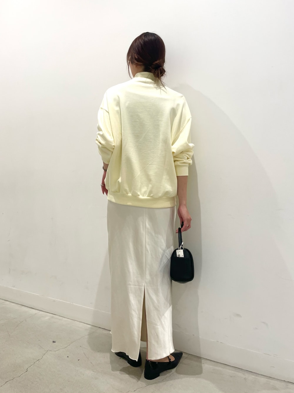 ブラック系のパンプス、ブラック系のハンドバッグ、ホワイト系のスカートを着用したレディースの春コーディネートの3枚目の写真