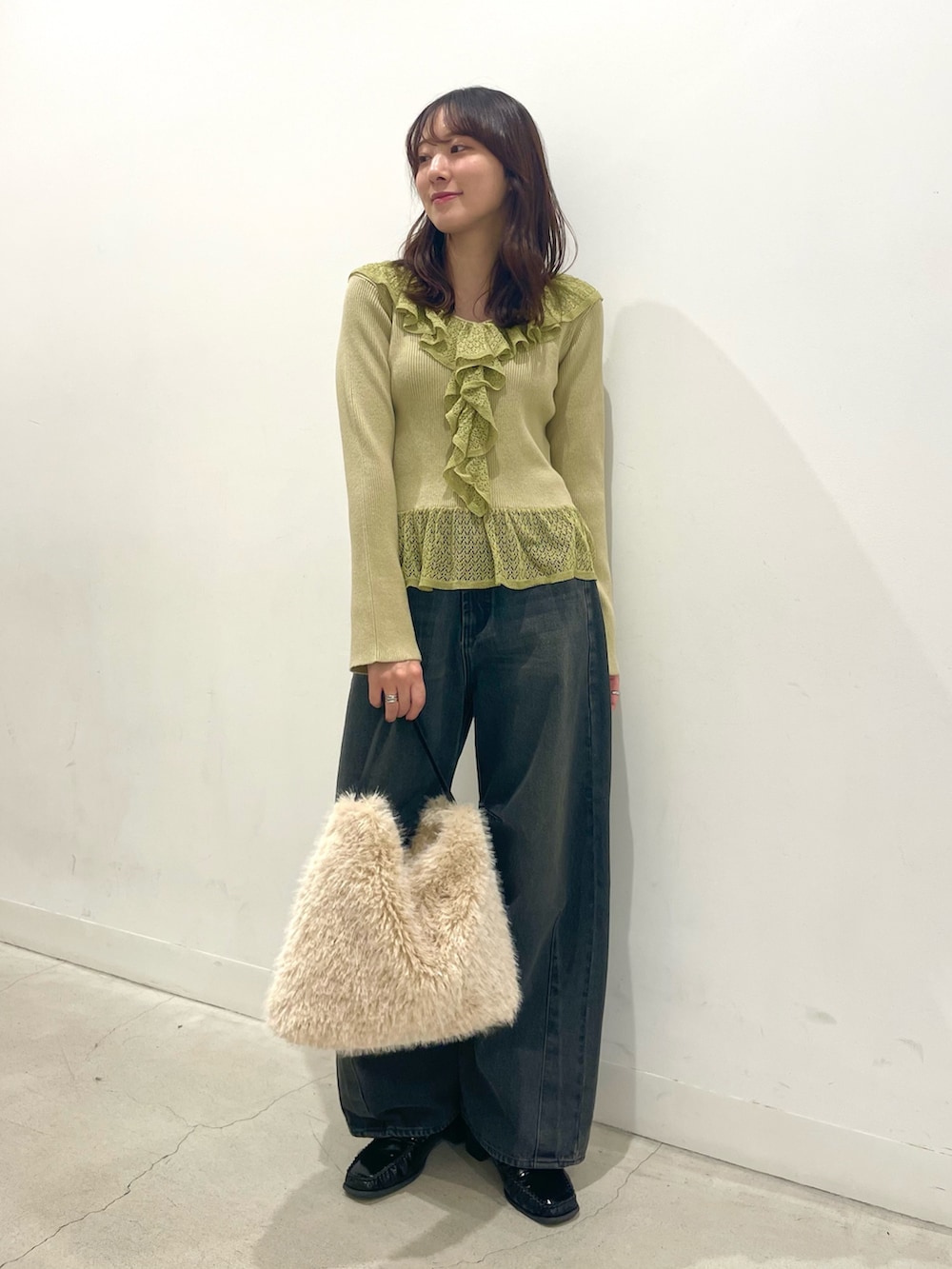 ブラック系のローファー、ホワイト系のハンドバッグ、グレー系のデニムパンツを着用したレディースの秋コーディネートの2枚目の写真