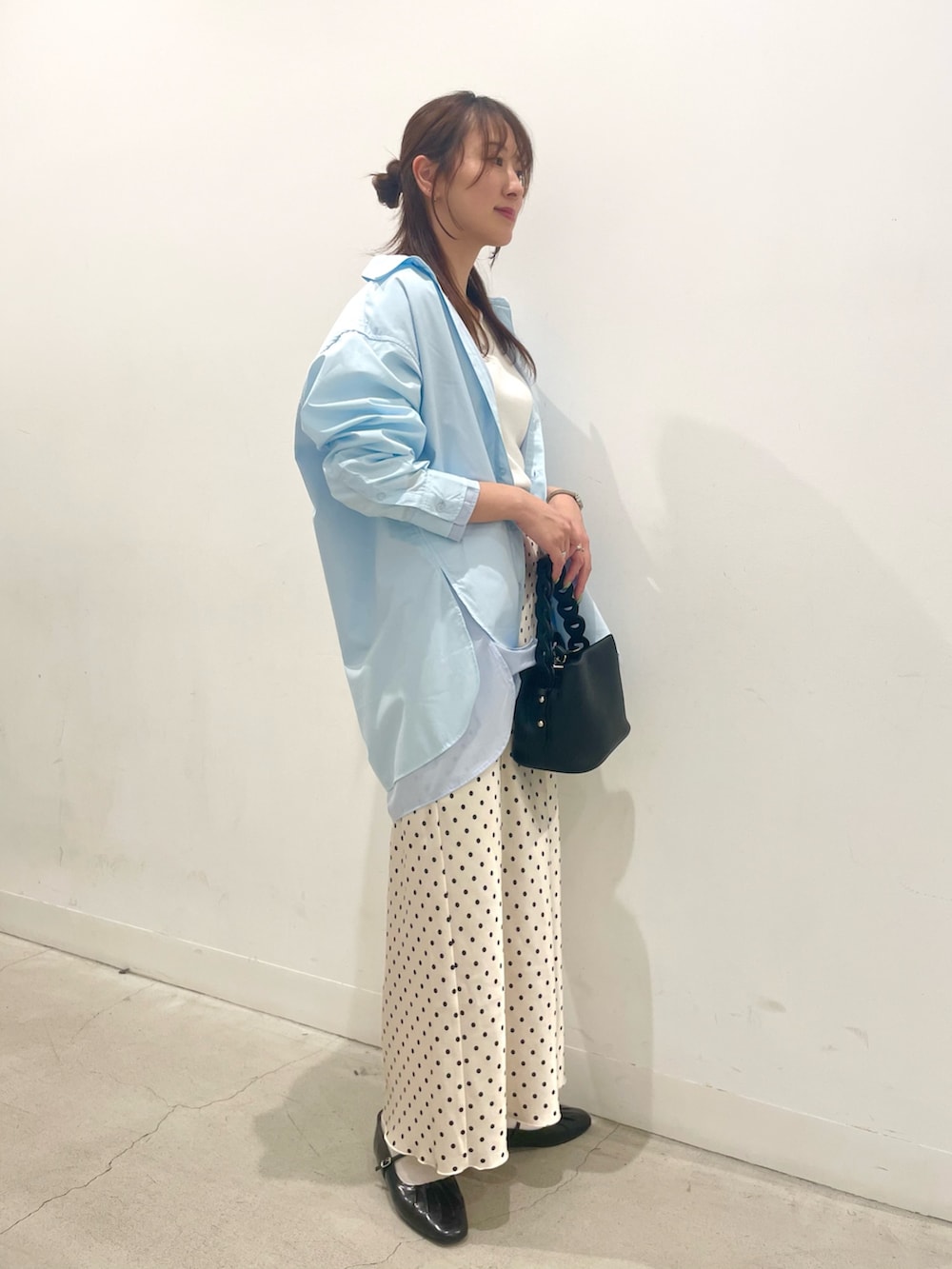 ブラック系のパンプス、ブラック系のショルダーバッグ、ホワイト系のスカートを着用したレディースの春コーディネートの2枚目の写真