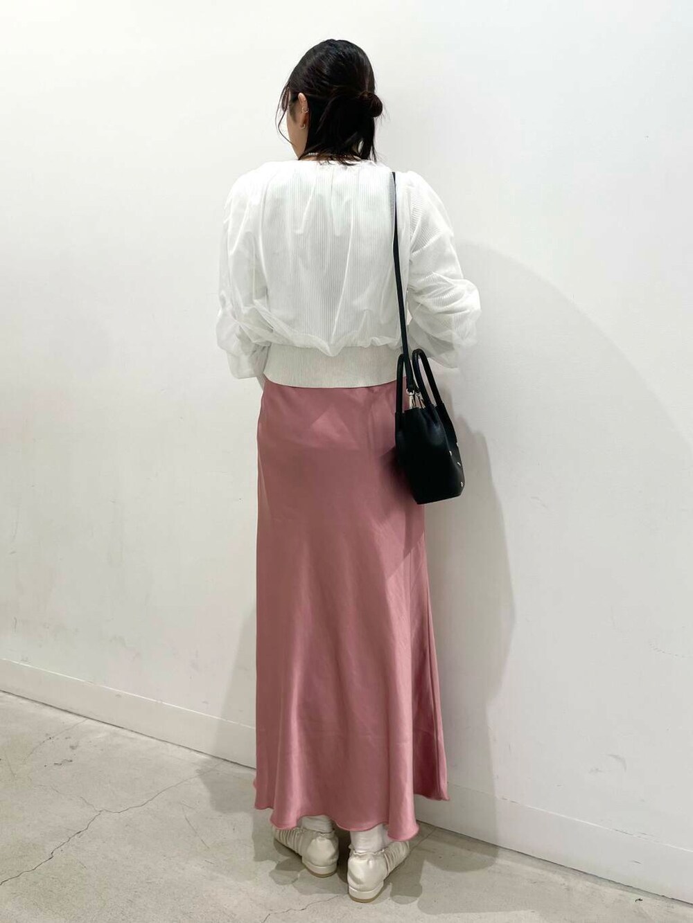 ピンク系のスカート、ブラック系のショルダーバッグ、ホワイト系のバレエシューズを着用したレディースの冬コーディネートの3枚目の写真