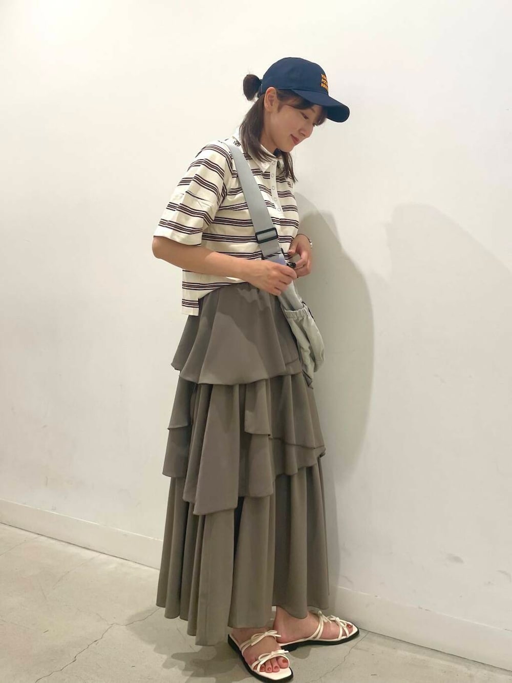 ベージュ系のショルダーバッグ、ブラウン系のスカート、ホワイト系のサンダルを着用したレディースの夏コーディネートの2枚目の写真