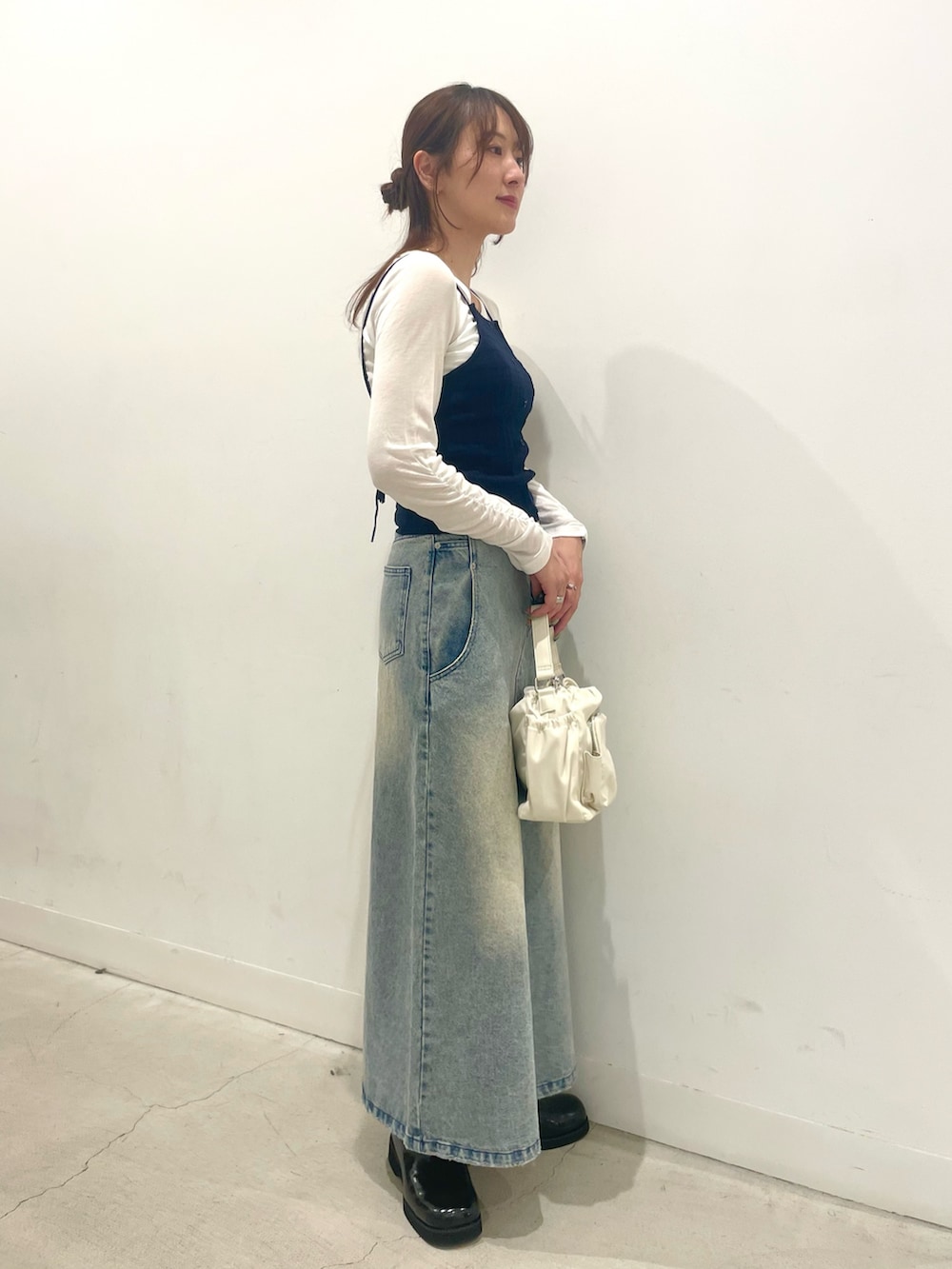 ブラック系のサンダル、ホワイト系のハンドバッグ、ブルー系のスカートを着用したレディースの春コーディネートの2枚目の写真
