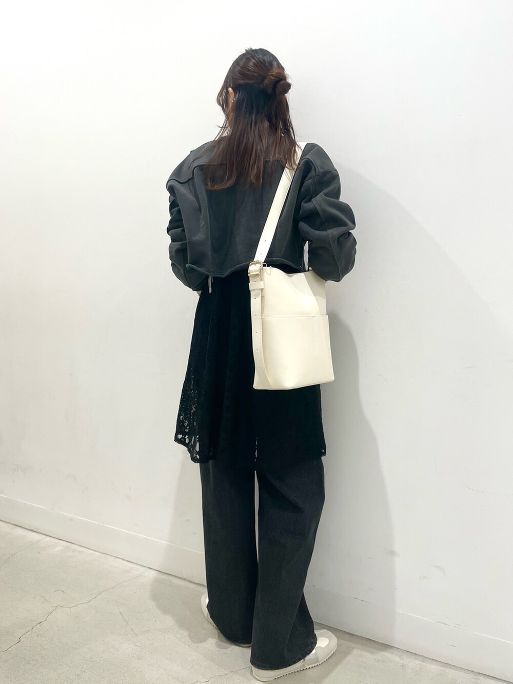 グレー系のスニーカー、ホワイト系のショルダーバッグ、ブラック系のデニムパンツを着用したレディースの冬コーディネートの3枚目の写真