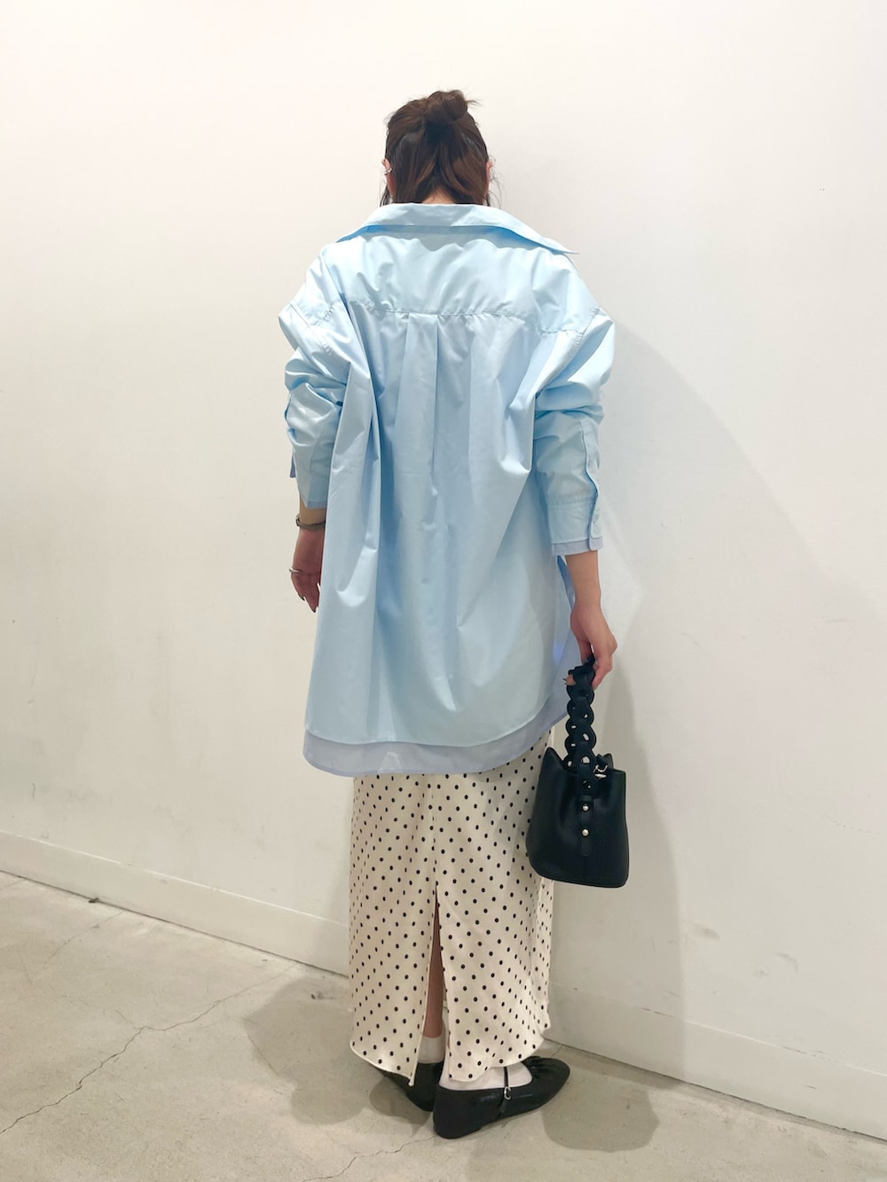 ブラック系のパンプス、ブラック系のショルダーバッグ、ホワイト系のスカートを着用したレディースの春コーディネートの3枚目の写真